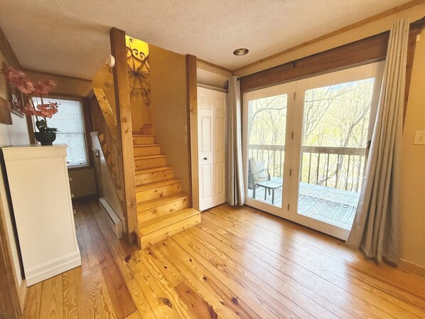 A wooden staircase leading to a balcony with a view of trees.