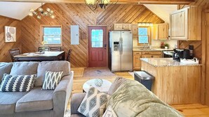 Interior acolhedor de uma cabana, com área de jantar, cozinha e sala de estar.