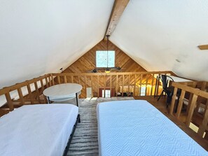 A cozy attic bedroom with two beds, a small table, and a chair. - * Plentiful Porches * Hot Tub * King Bed * Views * (Watauga County)