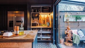 Une cuisine moderne dotée d’appareils électroménagers intégrés, d’un plan de travail en bois et offrant une vue sur l’extérieur.