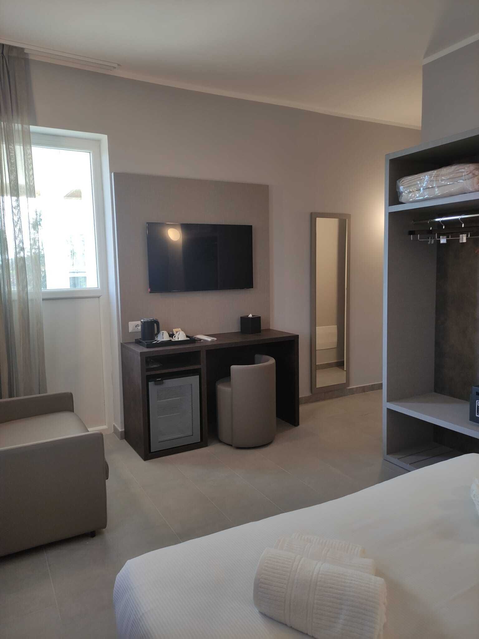 Une chambre d’hôtel moderne équipée d’un grand lit, d’un bureau avec un ordinateur, d’une télévision et d’une armoire.