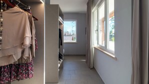 A hallway with a clothing rack, a window, and a door leading to another room. - Tiber Suite (Rome)
