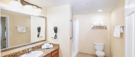 A bathroom with a sink, mirror, towel rack, shower, and toilet.
