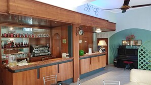 A bar area with wooden paneling, shelves with bottles and glasses, a clock, and a ceiling fan.