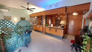 A reception area with a wooden counter, a ceiling fan, and a sign with initials.