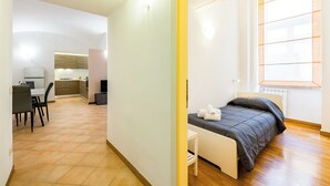 Ein modernes Hotelzimmer mit Bett, einem kleinen Tisch, einem Schreibtisch und Blick ins Freie.