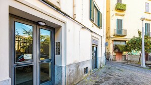 Eine enge Kopfsteinpflasterstraße mit einem Gebäude, das große Fenster und ein Schild für ein 'Ambulatorio Veterinario' hat.