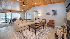 A spacious living room with a wooden ceiling, a large sofa, a coffee table, and a fireplace.