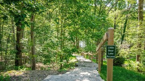 A stone pathway leading to Little Bear Lake Access, surrounded by dense forest.