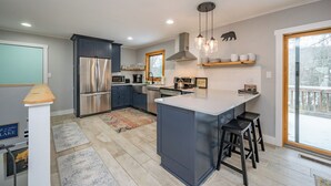 A modern kitchen with a central island, stainless steel appliances, and a large window providing a view of the outdoors.