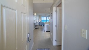A hallway leading to a kitchen and dining area with a view of the ocean.