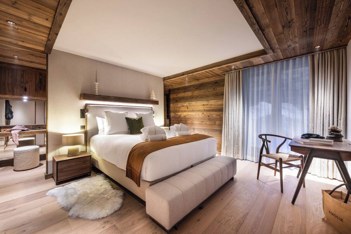 A modern bedroom with a large bed, bedside tables, a desk, and a chair.