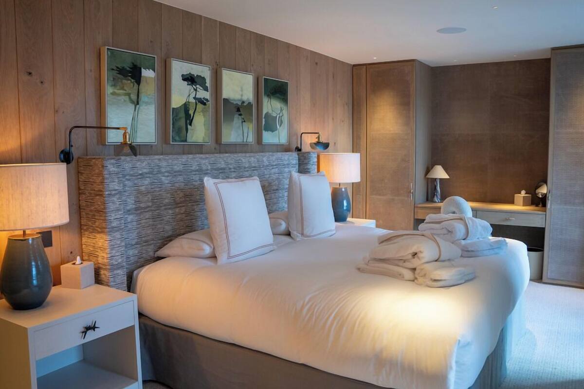 A hotel room with a large bed, two bedside tables with lamps, a nightstand, and artwork on the wall.
