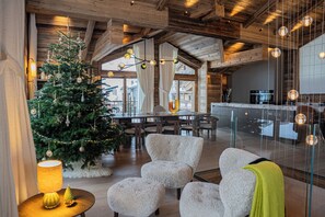A cozy interior with a wooden ceiling, a dining area, and a kitchen visible through a glass partition. - Silverstone by Alpine Resorts (Val-d'Isere)