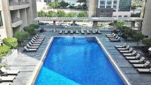 Une piscine rectangulaire à l’eau d’un bleu limpide, entourée de chaises longues et d’un espace de détente abrité.