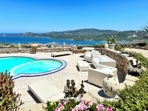 A pool area with a view of the sea and hills.