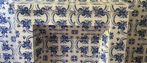 A tiled wall with a decorative pattern and a corner shelf.
