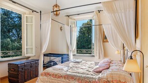 A bedroom with a four-poster bed, a suitcase, and a window with curtains. - *Elegant Villa*with Private Park-10 min from LUCCA (Capannori)