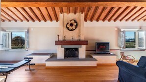 A living room with a fireplace, wooden beams, a bench, a sofa, and a TV. - *Elegant Villa*with Private Park-10 min from LUCCA (Capannori)