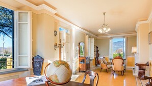 A spacious living room with a wooden table, chairs, a globe, and a view of the outdoors. - *Elegant Villa*with Private Park-10 min from LUCCA (Capannori)