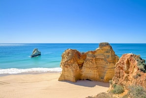 A beach with large rock formations and clear blue water. - Villa Praia in Albufeira (Albufeira)