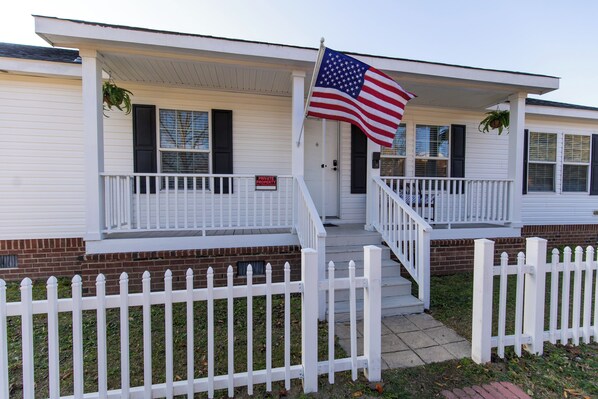 A two-story house with a white exterior, a front porch, and a white picket fence. - Hendrix Hideaway (Lexington)