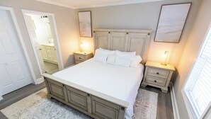 Ein Schlafzimmer mit einem großen Bett, zwei Nachttischen, einem Schminktisch und einem Fenster.
