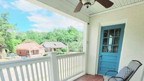 A covered porch with a ceiling fan, a blue door, and a brick floor. - Balcony Vibes and Blue Skies (Montgomery)