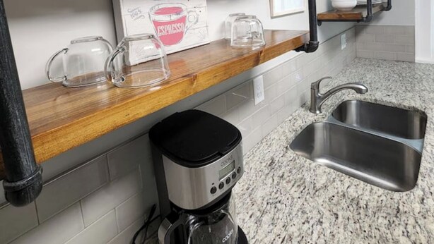 A kitchen with wooden shelves, a coffee maker, and a sink. - Balcony Vibes and Blue Skies (Montgomery)