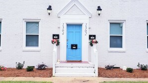 A white building with a blue door, numbered 1304 and 1302, and a small porch with steps. - Balcony Vibes and Blue Skies (Montgomery)