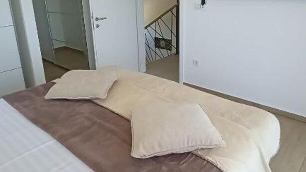Une chambre à coucher avec un lit, des oreillers, une télévision et un escalier menant à une autre pièce.