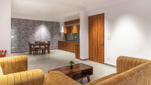 Un salon moderne comprenant un ensemble de canapés, une table à manger avec des chaises et un coin cuisine avec des meubles en bois et un plan de travail.