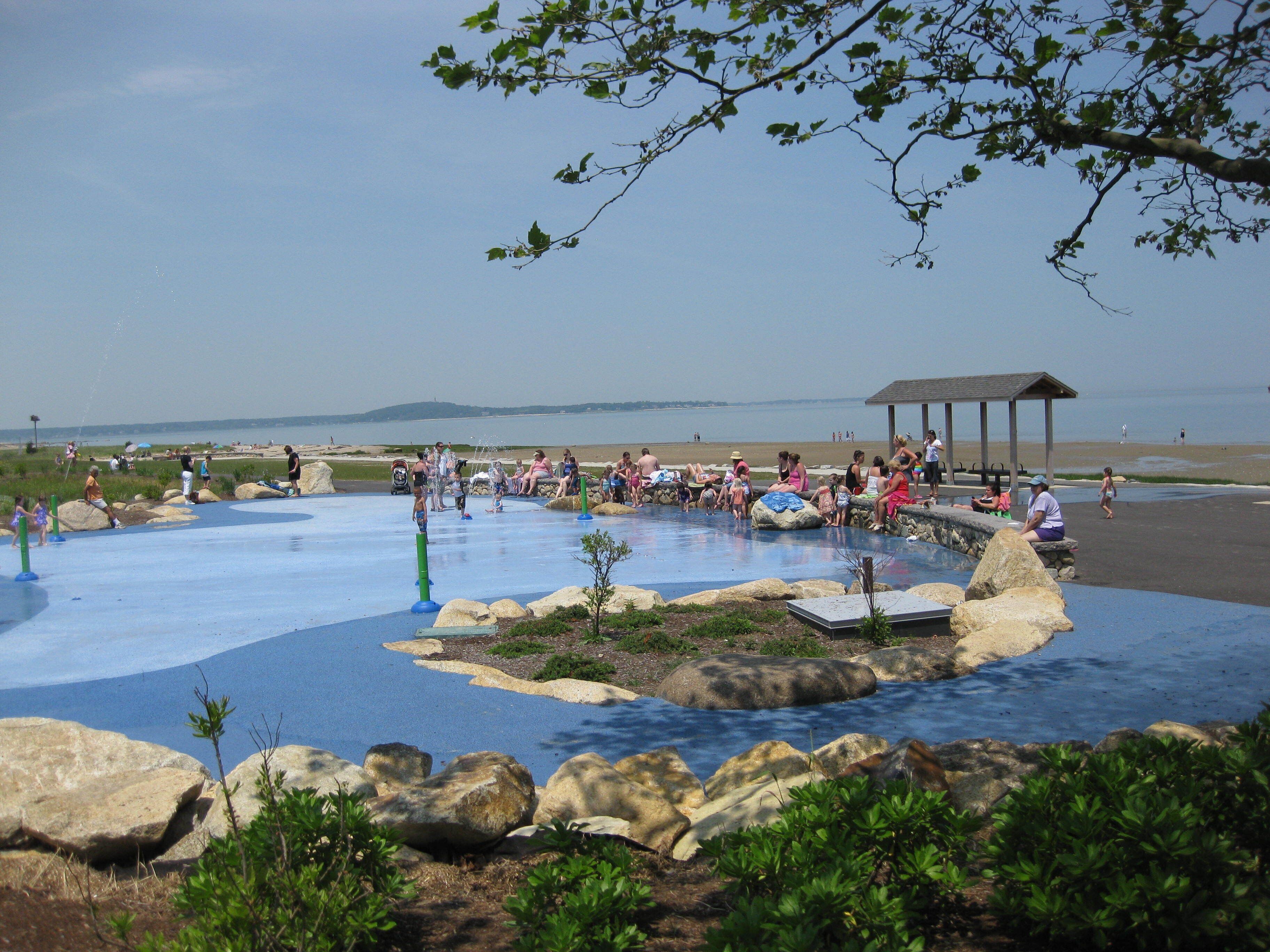 A water park with a pool, rocks, and a gazebo.