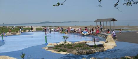 A water park with a pool, rocks, and a gazebo.