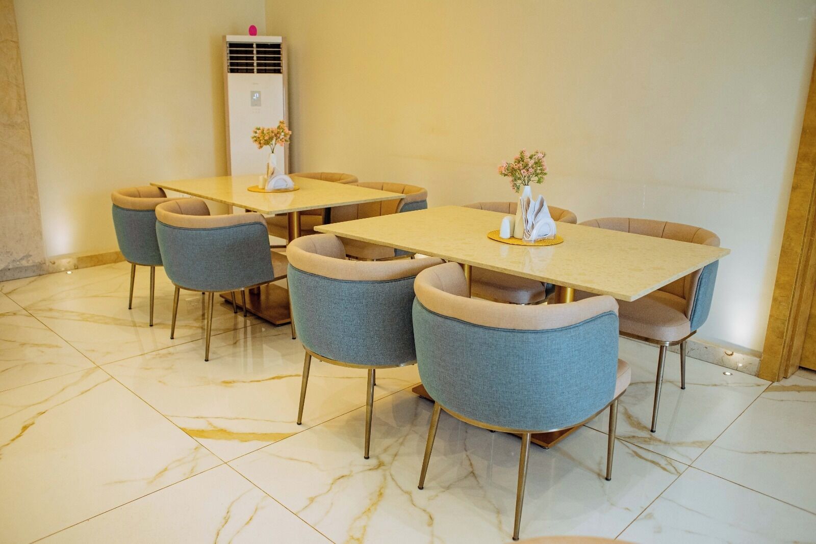 Un comedor con piso de baldosas de mármol, una mesa central con sillas y un aire acondicionado instalado en la pared.