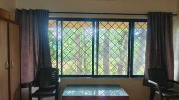 A room with a window, two chairs, a small table, and an air conditioning unit.