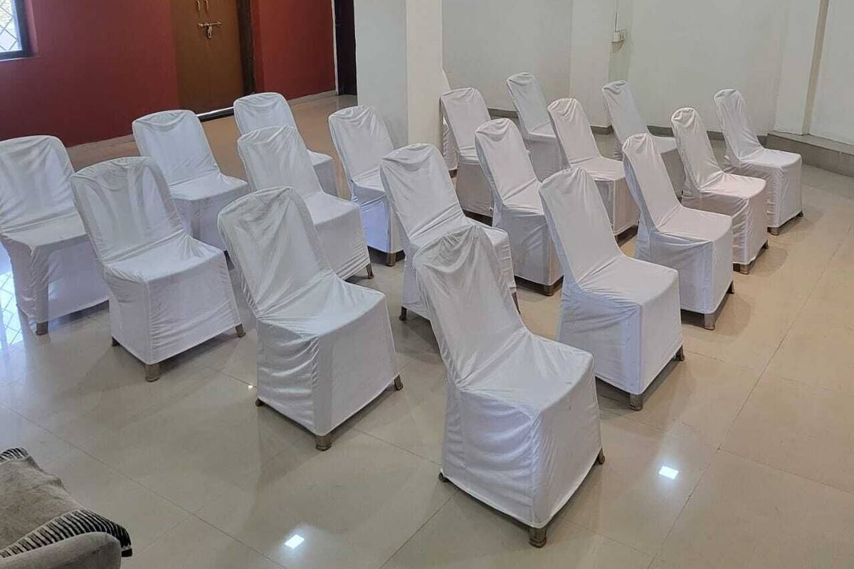 A room with rows of white-covered chairs arranged for an event.