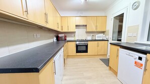 A modern kitchen with wooden cabinets, a black countertop, stainless steel appliances, and a white dishwasher. - RF-Entire House -Central Scotland-Falkirk| Self-Check-in |Pet-friendly | Parking (Falkirk)
