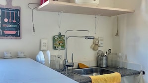 Et køkken med bordplade, vask og diverse hårde hvidevarer, herunder en blender og kaffemaskine.