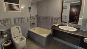 A bathroom with a toilet, bidet, bathtub, and sink. - Media International CoxsBazar  (Cox's Bazar)