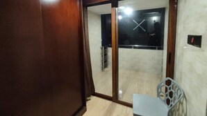 A room with a sliding glass door leading to a balcony, a wooden door frame, and a small chair. - Media International CoxsBazar  (Cox's Bazar)