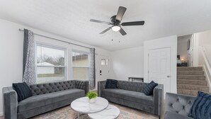 A living room with two grey sofas, a white coffee table, and a ceiling fan. - Pondside Retreat 4BR w/ Hot Tub & Pool Table & BBQ (Hilliard)