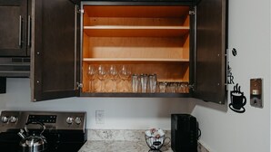A kitchen with a wooden cabinet containing wine glasses and a coffee machine. - Pondside Retreat 4BR w/ Hot Tub & Pool Table & BBQ (Hilliard)