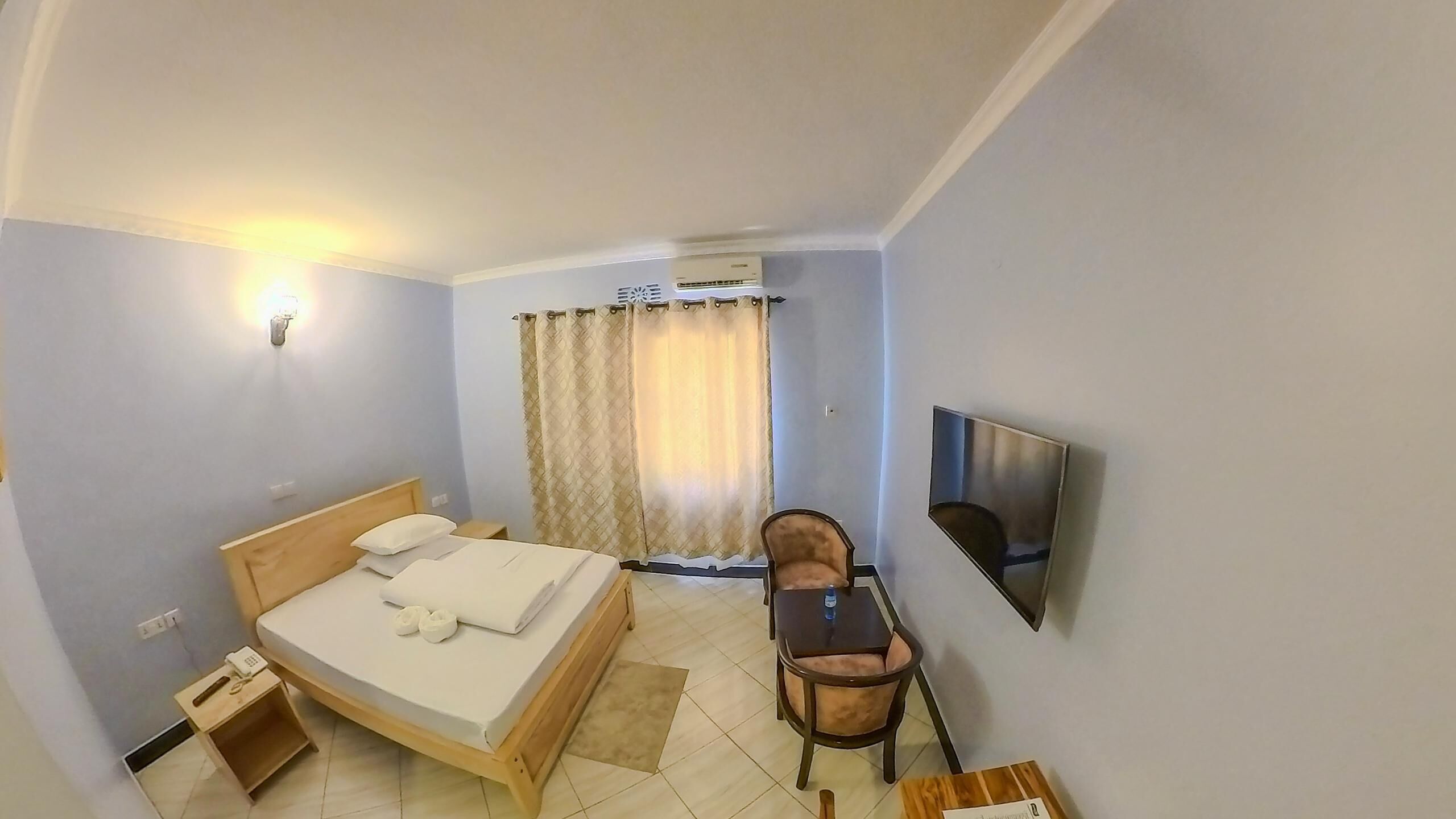 Une chambre d’hôtel équipée d’un lit, d’une chaise, d’un téléviseur et d’un appareil de climatisation.