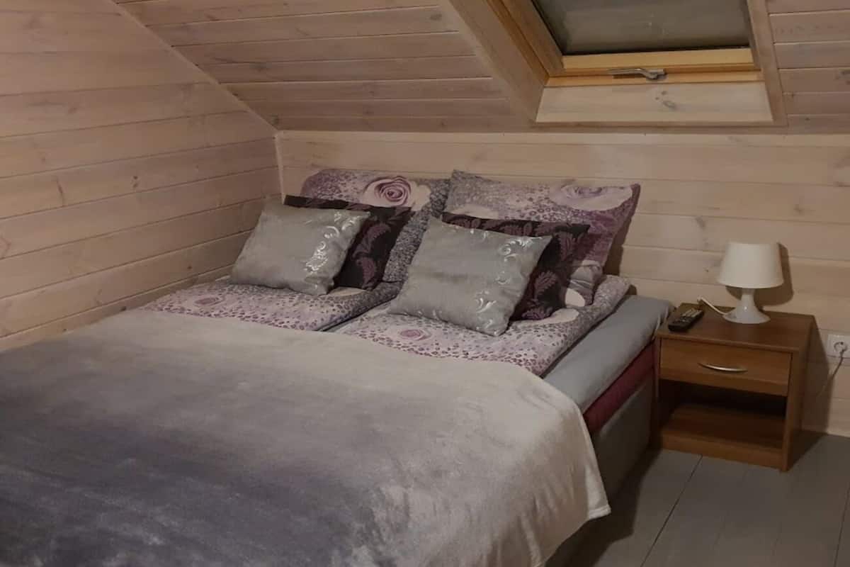 A cozy bedroom with a bed, pillows, a nightstand, and a lamp.