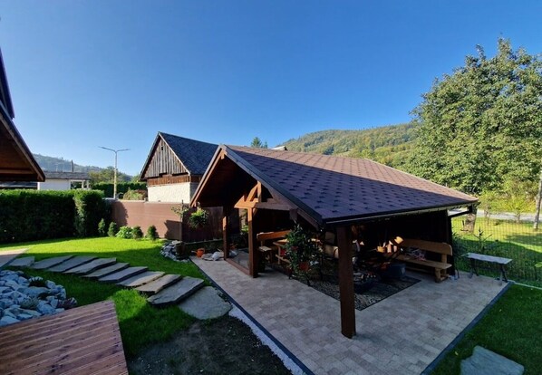 Uma casa de madeira rústica com varanda coberta, um caminho de pedra e um jardim bem cuidado.