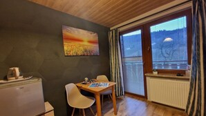 A compact room with a wooden ceiling, a dining table with two chairs, a radiator, and a window with blinds. - Pokoje Gościnne Kacper blisko Gondoli (Szczyrk)