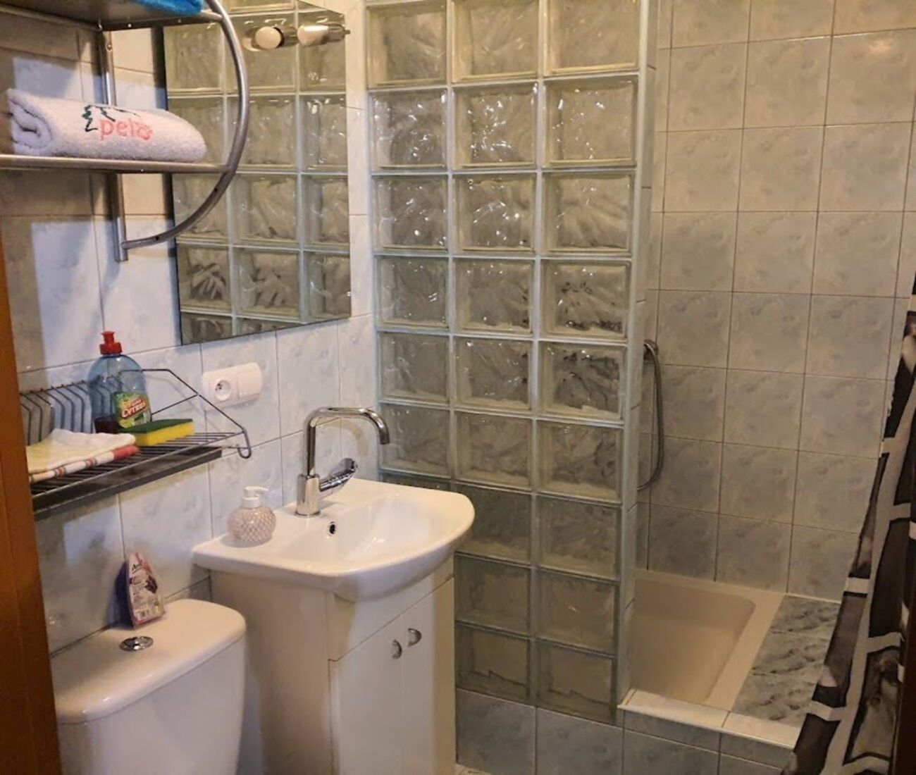 Un baño con cabina de ducha de vidrio, lavamanos blanco y retrete.