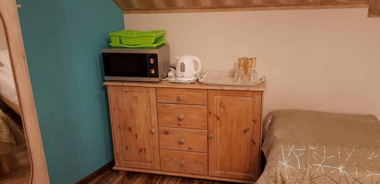 A wooden cabinet with a microwave, a kettle, and a tray with glasses.