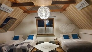 A cozy attic bedroom with two beds, a dining table, and a chandelier. - Pokoje Gościnne Kacper blisko Gondoli (Szczyrk)